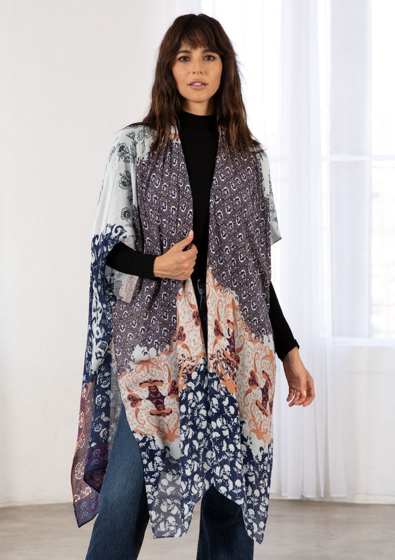 [Color: Midnight/Peach] A model wearing a soft and lightweight navy blue mid length kimono in a mixed bohemian print. With half length kimono sleeves, side slits, and an open front. 
