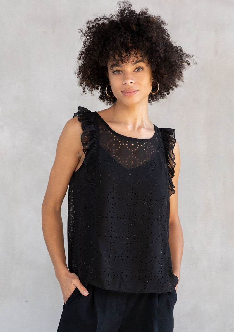 [Color: Black] A model wearing a black chiffon top with metallic laser cut detail. With a flutter cap sleeve and a back keyhole detail with button closure.