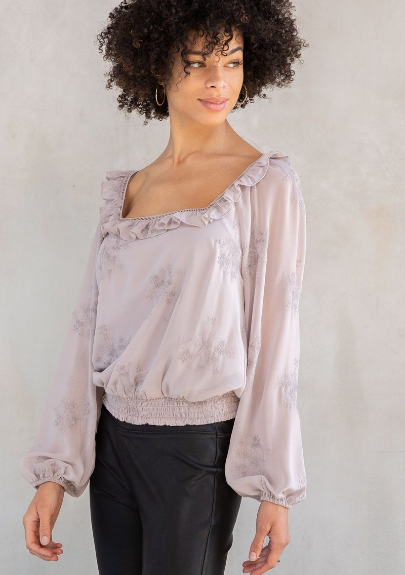 [Color: Dusty Mauve] A modal wearing a trendy light purple cropped bohemian top in floral embroidered chiffon. With a ruffle and lattice trimmed square neckline and voluminous long sleeves.