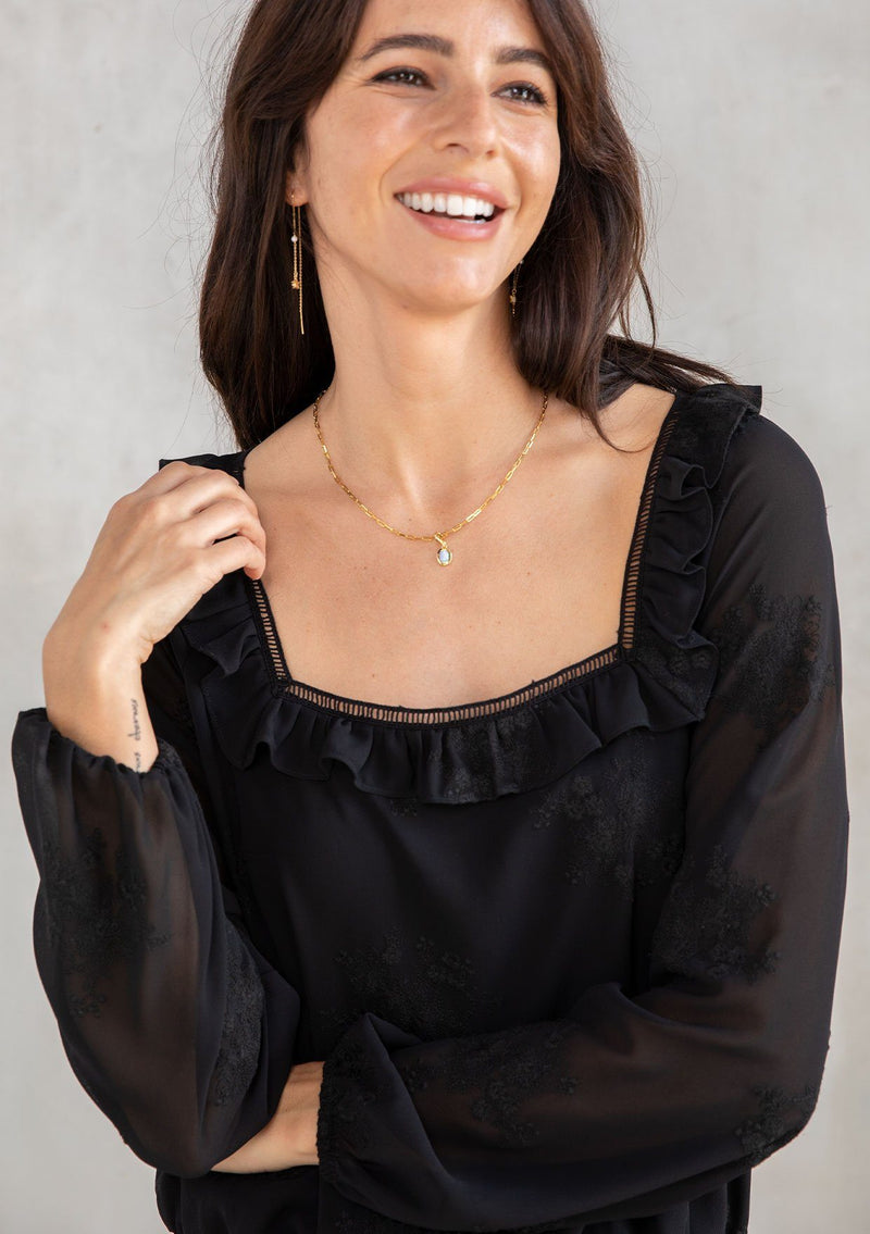 [Color: Black] A modal wearing a trendy black cropped bohemian top in floral embroidered chiffon. With a ruffle and lattice trimmed square neckline and voluminous long sleeves. 