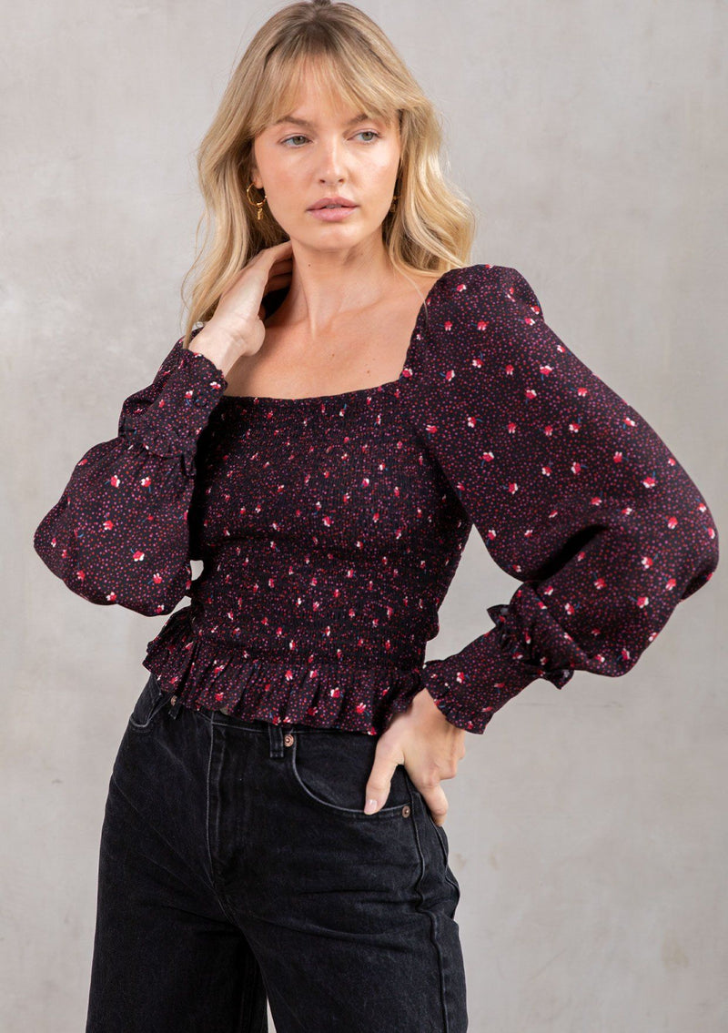 [Color: Black/Red] A model wearing a trendy cropped bohemian top in a black and red dot floral print. With a smocked bodice, square neckline and long voluminous sleeves. 