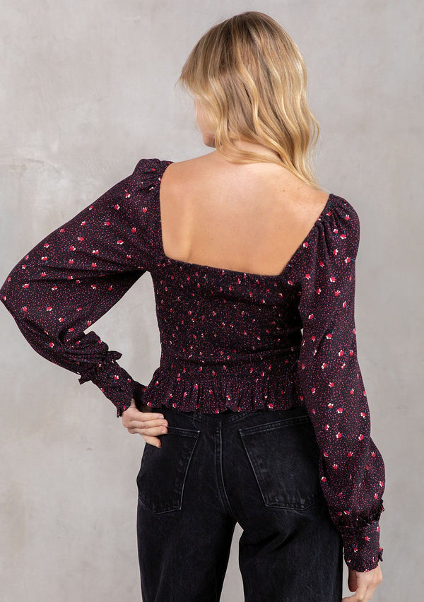 [Color: Black/Red] A model wearing a trendy cropped bohemian top in a black and red dot floral print. With a smocked bodice, square neckline and long voluminous sleeves. 