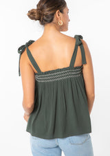 [Color: Military] A woman wearing a green crinkle gauze flowy bohemian tie shoulder tank top with smocked neckline. 