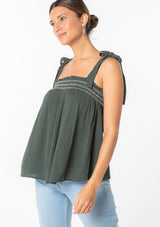 [Color: Military] A woman wearing a green crinkle gauze flowy bohemian tie shoulder tank top with smocked neckline. 