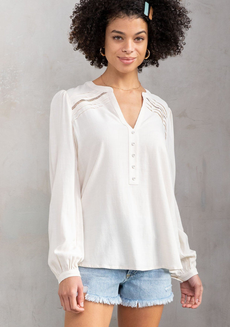 [Color: Vanilla] A model wearing a timeless long sleeve off white linen blend blouse. With a decorative button front, delicate lattice trim, and pleated details. 