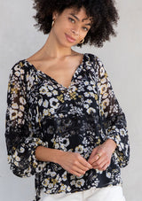 [Color: Black/Lemon] A model wearing a lightweight sheer chiffon peasant top in black and yellow floral print. With long sleeves and a split neckline with ties. 