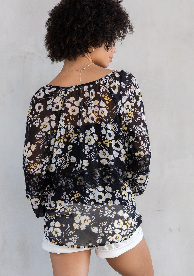 [Color: Black/Lemon] A model wearing a lightweight sheer chiffon peasant top in black and yellow floral print. With long sleeves and a split neckline with ties. 