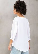 [Color: Chalk] A model wearing a silky white blouse with rolled tab sleeves, a front patch pocket, and a split v neckline. Classic top for the office.