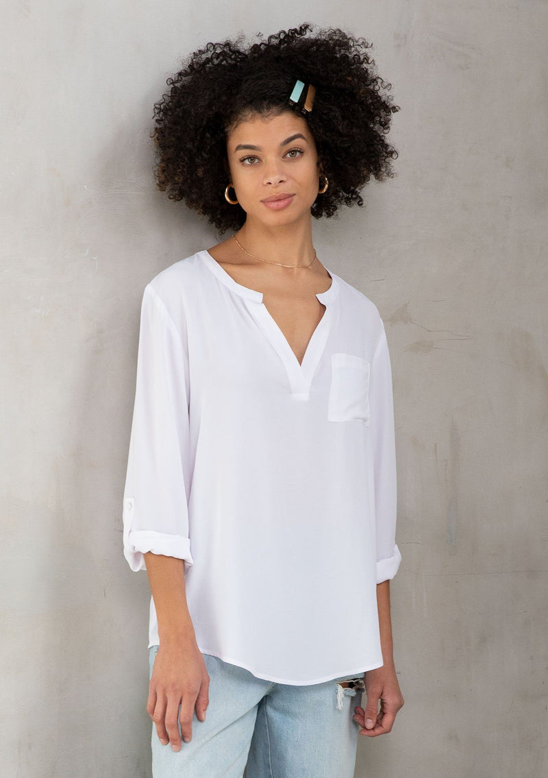 [Color: Chalk] A model wearing a silky white blouse with rolled tab sleeves, a front patch pocket, and a split v neckline. Classic top for the office.