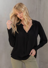 [Color: Black] A model wearing a classic black peasant top, designed in silky crepe. Featuring a split v neckline with ties and long voluminous sleeves.