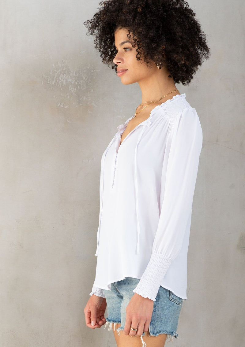 [Color: Chalk] A model wearing a classic white peasant top, designed in silky crepe. Featuring a split v neckline with ties and long voluminous sleeves.