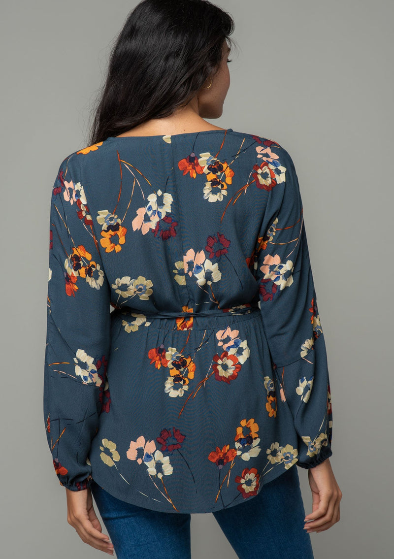 [Color: Grey/Wine] A back facing image of a brunette model wearing a slate blue grey long sleeve wrap top with a wine red floral print. 