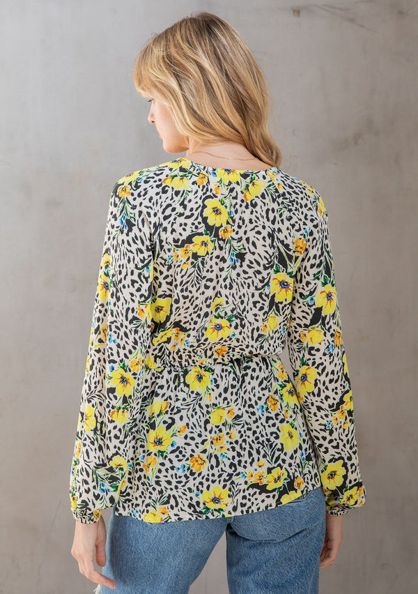 [Color: Ivory/Lemon] A model wearing a pretty yellow floral print top with a button front, long volume sleeves, and tie front detail. 