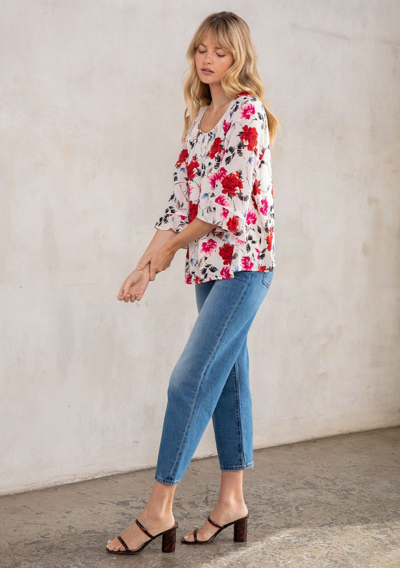 [Color: Cream/Red] A model wearing a romantic red rose floral print blouse, with bohemian three quarter length flutter sleeves and a round neckline. 