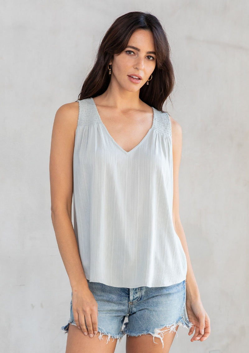 [Color: Sage] A model wearing an ultra soft and lightweight sage green tank top in subtle striped jacquard. With a loose and flowy silhouette, a v neckline, and smocked yoke detail.