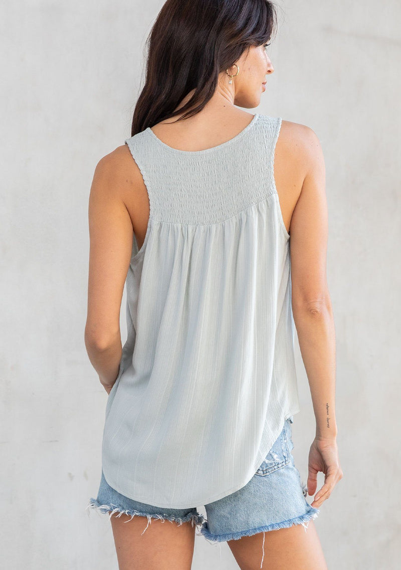 [Color: Sage] A model wearing an ultra soft and lightweight sage green tank top in subtle striped jacquard. With a loose and flowy silhouette, a v neckline, and smocked yoke detail.