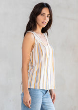 [Color: Dijon/Off White] A model wearing an ultra soft and lightweight Summer tank top in a white and yellow stripe. With a loose and flowy silhouette, a v neckline, and smocked yoke detail. 