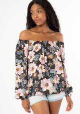 [Color: Charcoal/Rose] A black model with long wavy hair wearing a flowy bohemian top with long sleeves and a wide, round elastic neckline that can be worn on or off the shoulder. Worn here off the shoulder. 
