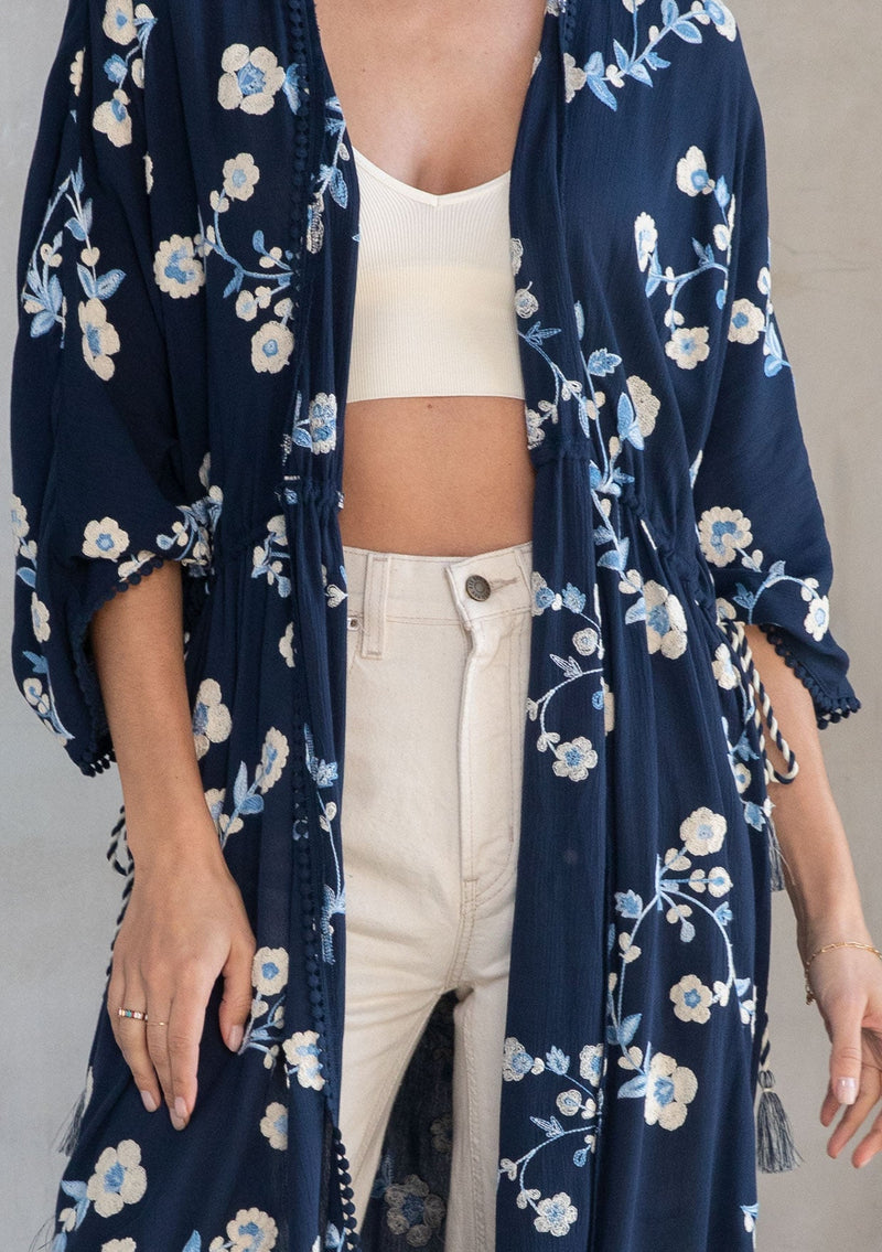 [Color: Navy/Ivory] A model wearing a bohemian navy blue mid length kimono with floral embroidery. 