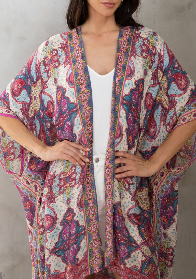 [Color: Blue/Fuchsia] A model wearing a dreamy blue and pink mixed print mid length kimono. A lightweight and soft bohemian style with half length sleeves, an open front, and side slits.