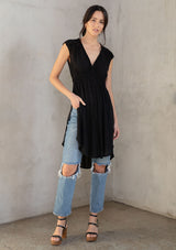[Color: Black] A model wearing a floaty black bohemian sheer cap sleeve tunic top with button front and braided trim. 