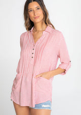 [Color: Red/Ivory] A model wearing a relaxed yarn dye popover tunic shirt in a red and ivory stripe. With long rolled sleeves, a button front, and two patch pocket details.