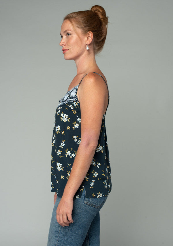 [Color: Navy/Powder Blue] A side facing image of a red headed model wearing a bohemian navy blue, yellow, and white floral print camisole tank top. With a lace trim v neckline, a self covered button front, and adjustable spaghetti straps. 