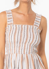 [Color: Natural/Tan] A woman wearing a brown and off white yarn dye stripe tank top with a slim fit smocked bodice and tank top straps. 