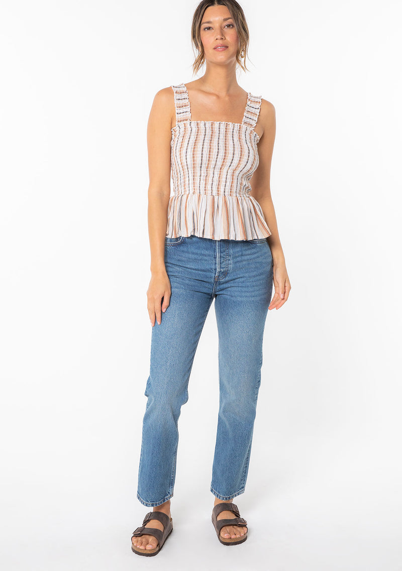 [Color: Natural/Tan] A woman wearing a brown and off white yarn dye stripe tank top with a slim fit smocked bodice and tank top straps. 