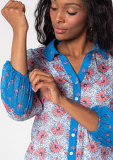 [Color: Ivory/Blue] A model wearing a blue, white and red mixed floral print sheer chiffon button front blouse. A vintage inspired shirt with contrast sleeve detail and classic collared neckline. 