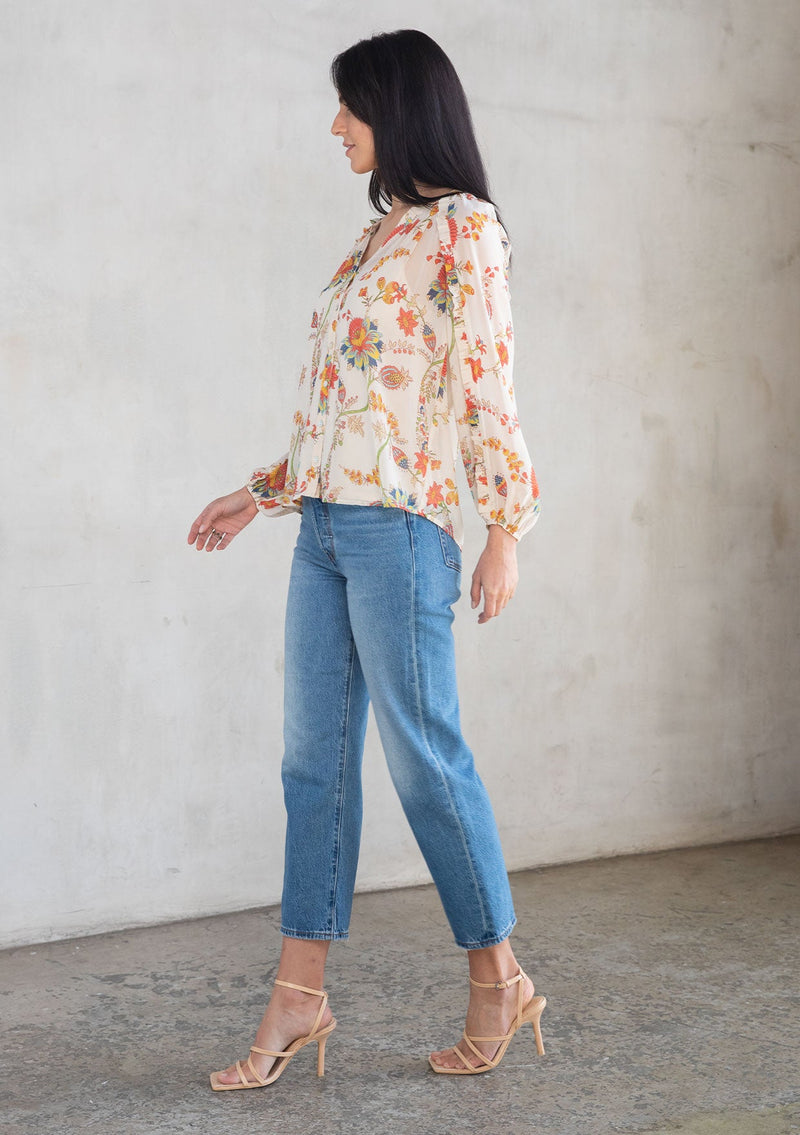 [Color: Ivory/Coral] A model wearing a sheer chiffon button front flowy bohemian top in a floral print. With long sleeves and ruffled trim. 