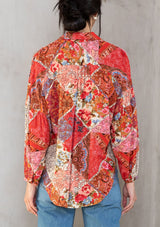 [Color: Ivory/Red] A model wearing a red bohemian button up shirt in a floral patchwork print. With a split collared v neckline and voluminous long sleeves. 