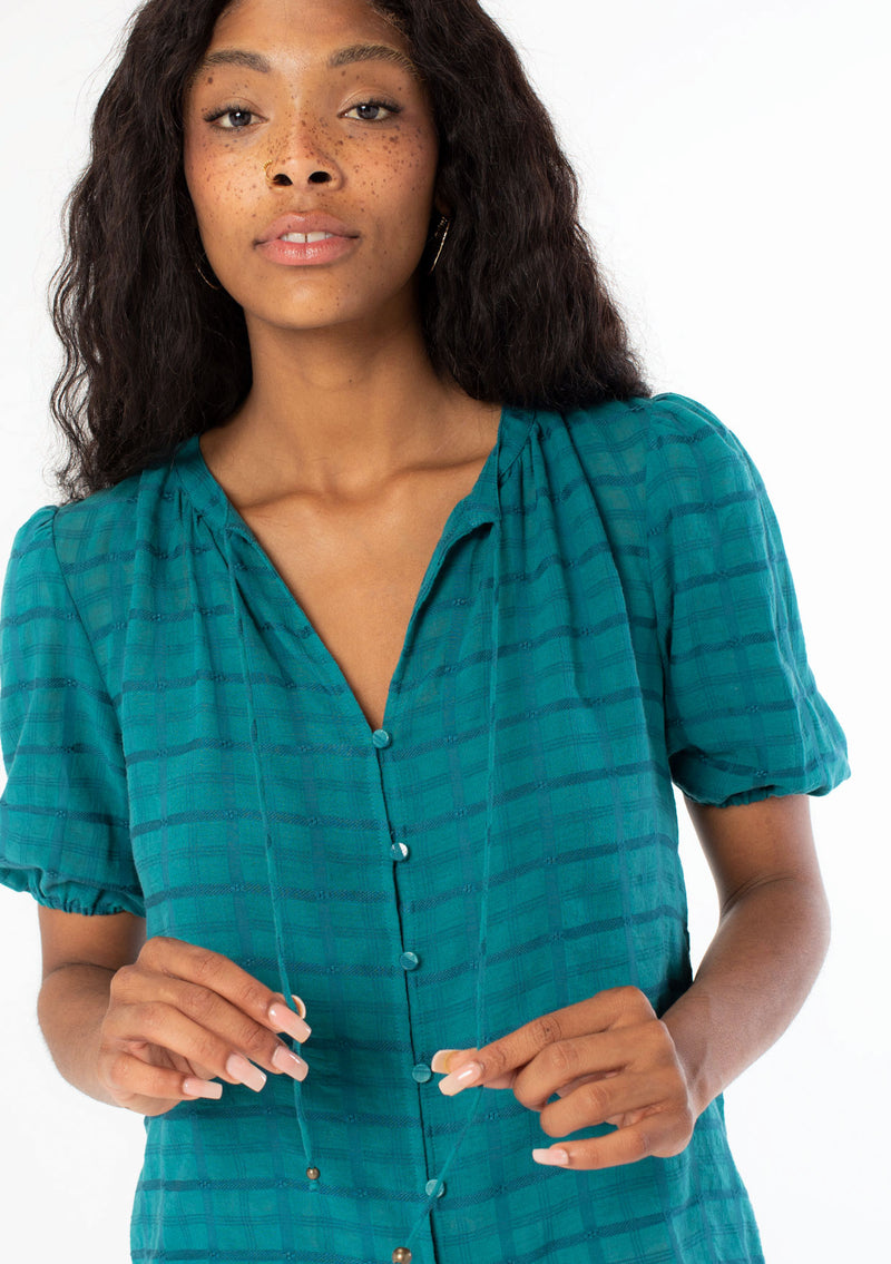 [Color: Teal] A close up image of a black model wearing a bohemian teal cotton button front top with short puff sleeves.
