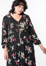 [Color: Black/Red] A model wearing a dreamy black bohemian maxi kimono with a pink floral print. With long sleeves, high slits, and a self covered button front top.