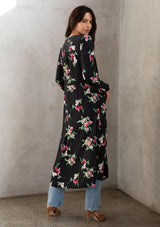 [Color: Black/Red] A model wearing a dreamy black bohemian maxi kimono with a pink floral print. With long sleeves, high slits, and a self covered button front top. 