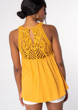 [Color: Butterscotch] A model wearing a golden yellow crochet yoke tank top with a racerback and a flowy fit.