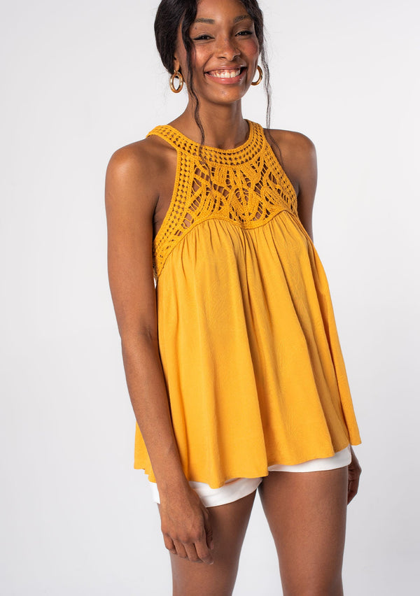 [Color: Butterscotch] A model wearing a golden yellow crochet yoke tank top with a racerback and a flowy fit.
