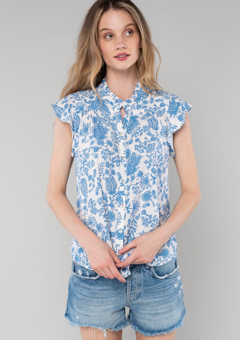 [Color: Cream/Dusty Blue] A front facing image of a blonde model wearing a classic best selling bohemian button front top in a cream and blue floral print. With short flutter cap sleeves and a ruffled neckline. 
