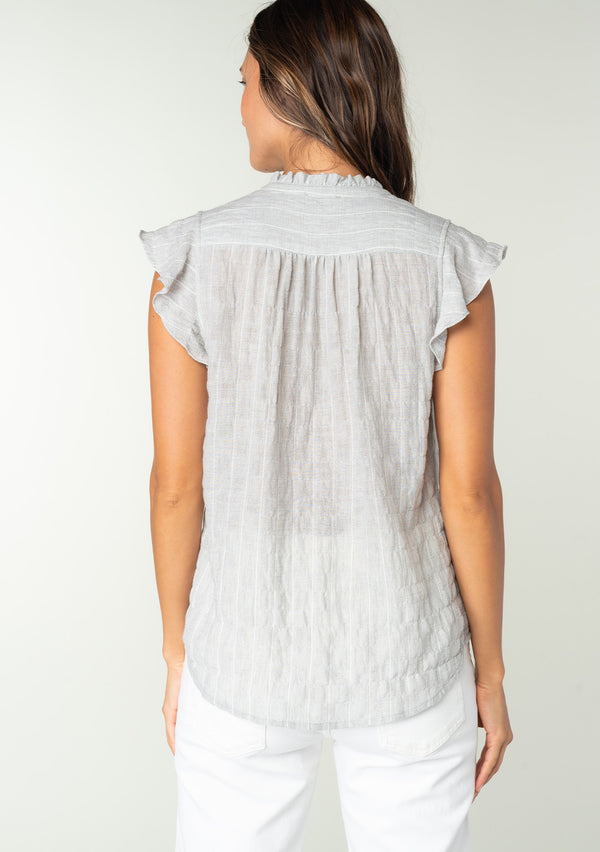 [Color: Heather Grey] A back facing image of a brunette model wearing a sheer cotton button front top in a striped jacquard. With short flutter sleeves and a ruffled neckline. A best selling bohemian top. 