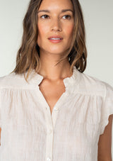 [Color: Oatmeal] A close up front facing image of a brunette model wearing a sheer cotton button front top in a striped jacquard. With short flutter sleeves and a ruffled neckline. A best selling bohemian top. 