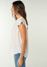 [Color: Oatmeal] A side facing image of a brunette model wearing a sheer cotton button front top in a striped jacquard. With short flutter sleeves and a ruffled neckline. A best selling bohemian top. 