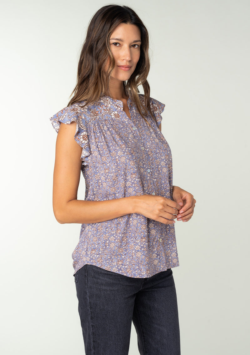 [Color: Grey/Natural] A side facing image of a brunette model wearing a best selling Lovestitch button front top in a grey and natural floral print. With short flutter sleeves and a ruffled neckline. 