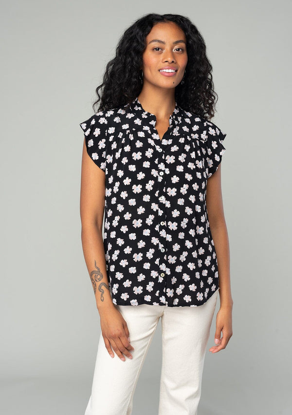 [Color: Black/Taupe] A front facing image of a brunette model wearing a best selling bohemian blouse in a black and taupe floral print. With a button front and short flutter cap sleeves. 