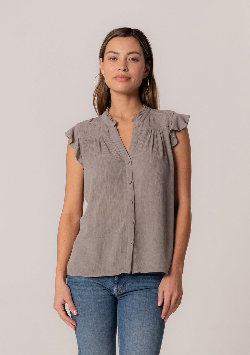 [Color: Cement] A front facing image of a brunette model wearing a grey crinkle gauze short sleeve flutter top with a button front and a ruffled neckline.