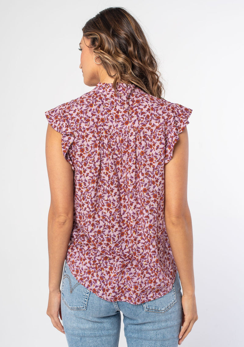 [Color: Lavender/Purple] A woman wearing a purple floral print bohemian button up top with short flutter sleeves and gold lurex details throughout. 