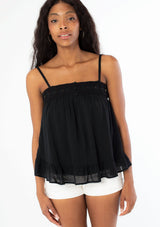 [Color: Black] A woman wearing a black flowy bohemian tank top with crochet trim, gold toned hardware, and adjustable spaghetti straps.