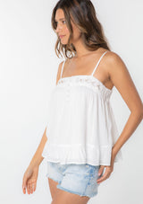 [Color: White] A woman wearing a white flowy bohemian tank top with crochet trim, gold toned hardware, and adjustable spaghetti straps. 