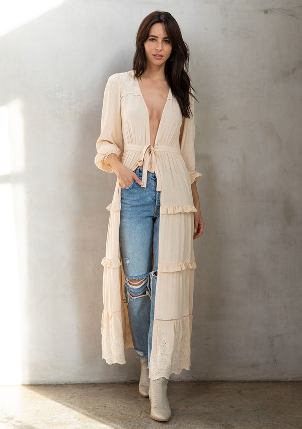 [Color: Natural] A model wearing a stunning natural maxi length kimono with embroidered detail, long sleeves, and a tie front detail. A bohemian duster that pairs well with denim.