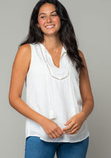 [Color: Off White] A front facing image of a brunette model wearing a white eyelet bohemian tank top. With a split v neckline and tassel ties. 