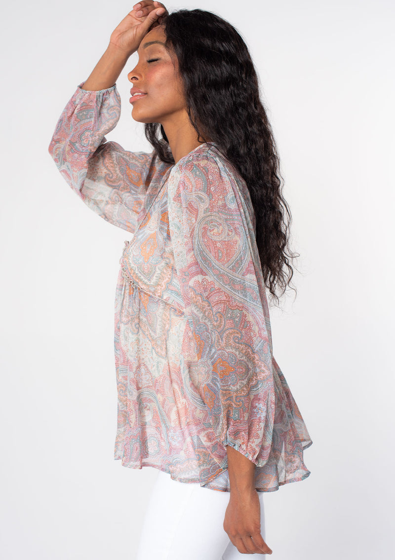 [Color: Blush/Aqua] A model wearing a sheer pink and blue paisley print bohemian blouse with long sleeves and ruffled accents. A dreamy Spring tunic top in sheer chiffon. 